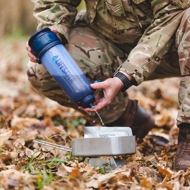 Load image into Gallery viewer, Person in camouflage clothing using a LifeSaver Bottle outdoors.