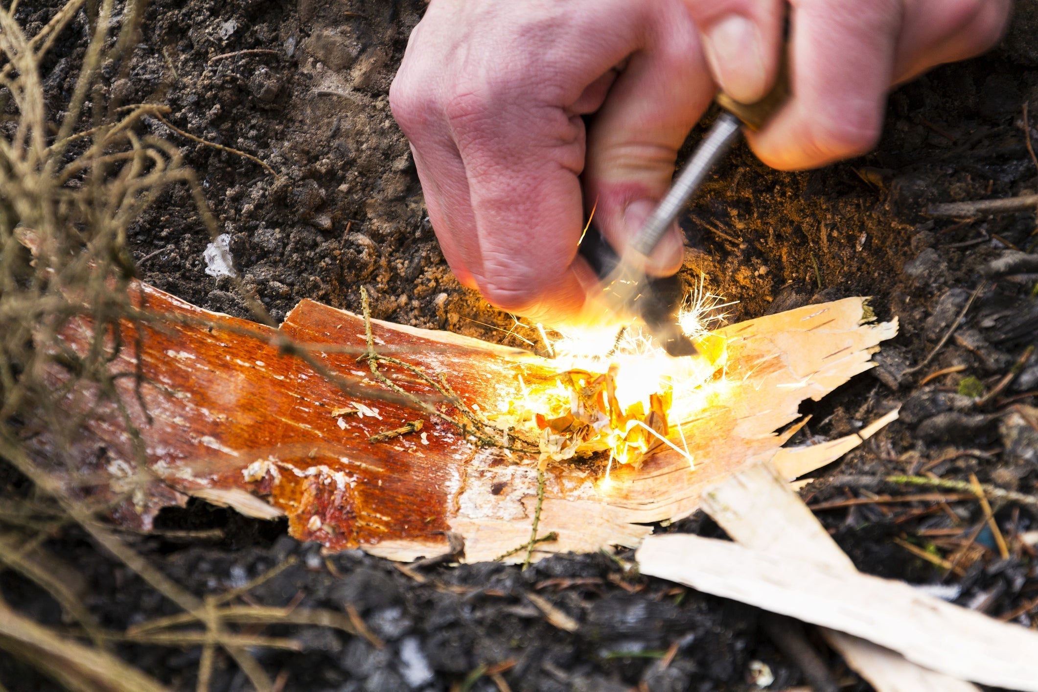 A man using a firelighter to start a campfire