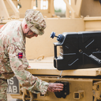 Soldier in camouflage uniform filling a cup from a black LifeSaver Jerrycan on a military vehicle