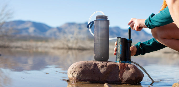 LifeSaver Wayfarer filling a bottle with purified water drawn from a lake
